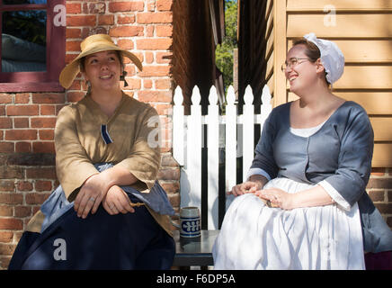 Two young smiling women in period costume at Colonial Williamsburg, Virginia, USA Stock Photo