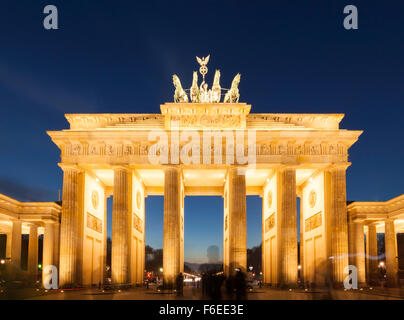 Berlin, illuminated Brandenburg Gate at dusk, long exposure shot with ghosted silhouettes of tourists in front Stock Photo