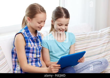 happy girls with tablet pc sitting on sofa at home Stock Photo