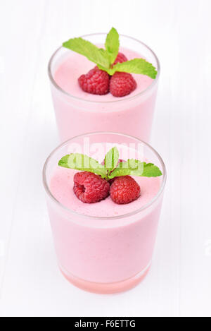Raspberry smoothie in glass on white background