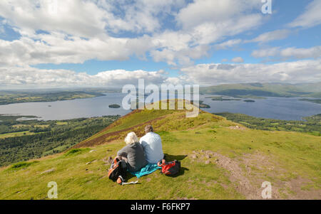 Two walkers enjoying view of Loch Lomond - and geographical highland boundary  fault line running across it - from Conic Hill Stock Photo
