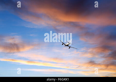 Airplane Flying in Sunset clouds Stock Photo