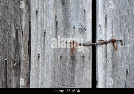 Close up of a rusty old hook on weathered barn door. Stock Photo
