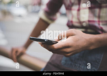 Close up on the hand of a young handsome afro black man using a smartphone, tapping the screen - technology, social network, communication concept Stock Photo