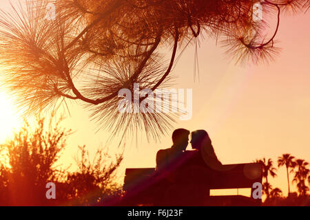 A pregnant couple sitting on a bench during a romantic warm sunset at a Park in Phoenix, Arizona Stock Photo