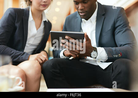 Close up shot of african business man showing something on digital tablet to his female colleague. Business people meeting in a