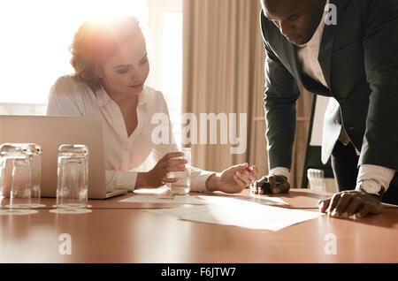 Two young business colleagues working on some business ideas. Entrepreneurs analyzing business reports on conference table. Stock Photo
