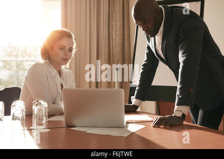 Two business people looking at business plan on laptop. Businessman and businesswoman in conference room working on business str Stock Photo