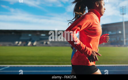 Side view of fit young woman running. African female athlete training on race track at athletics stadium. Stock Photo