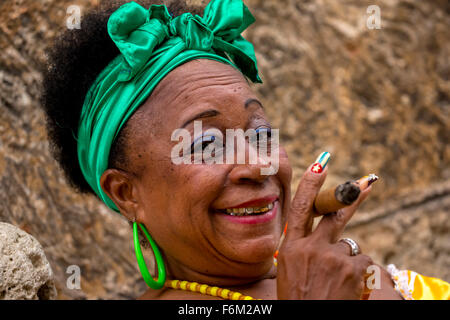 old heavily made Cuban woman with green hair bow smoking a Havana cigar, Cuban cigar with lacquered fingernails with Cuban Flag, Stock Photo