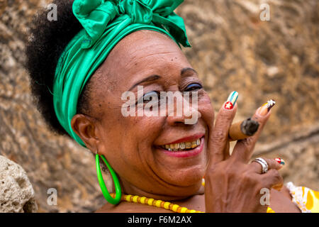 old heavily made Cuban woman with green hair bow smoking a Havana cigar, Cuban cigar with lacquered fingernails with Cuban Flag, Stock Photo