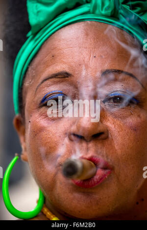 old heavily made Cuban woman with green hair bow smoking a Havana cigar, Cuban cigar with lacquered fingernails with Cuban Flag, Stock Photo