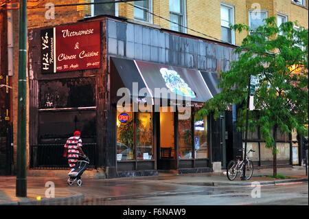 Following a summer evening storm in Chicago's Uptown neighborhood on Argyle Street a lone pedestrian proceeds down a sidewalk. Chicago, Illinois, USA. Stock Photo