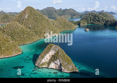 Forest-covered limestone islands surround a gorgeous lagoon in a remote part of Raja Ampat, Indonesia. This beautiful region is Stock Photo