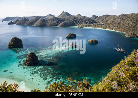 Forest-covered limestone islands surround a gorgeous lagoon in a remote part of Raja Ampat, Indonesia. This beautiful region is Stock Photo