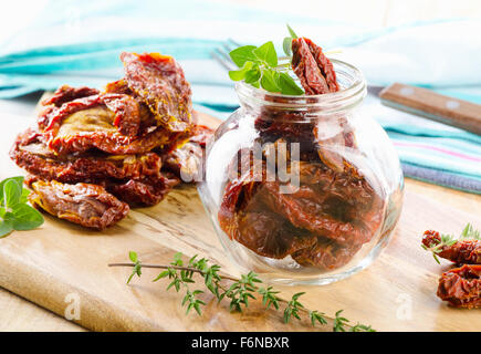 Italian sun dried tomatoes in glass jar on a wooden table. Selective focus Stock Photo