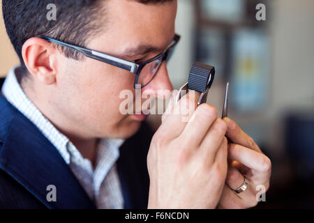 Jeweler examining diamond thoroughly through loupe Stock Photo