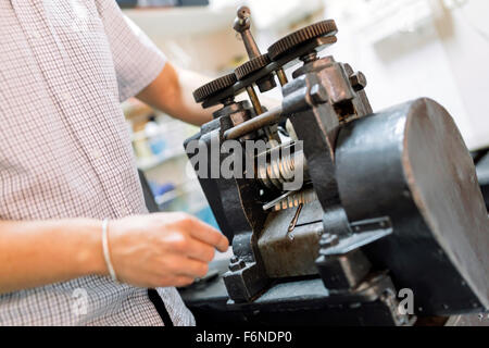 Goldsmith using machine to make metal thinner Stock Photo