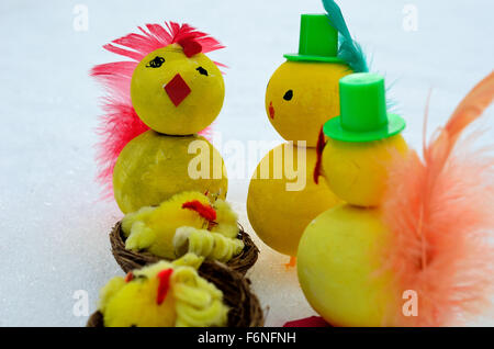 Yellow homemade easter chickens with top hats and newborn in basket on snow Stock Photo