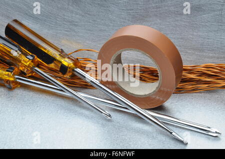 Screwdrivers insulating tape and cables on metal surface with place for text Stock Photo