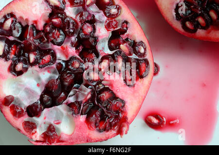 Juicy and sweet Pomegranate apple sliced in half close up on white plate Stock Photo