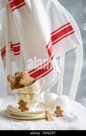 Freshly baked gingerbread men sitting in vintage teacups on festive chair Stock Photo