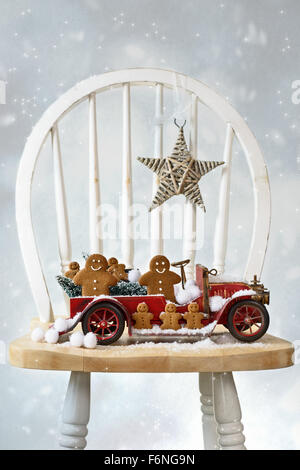 Festive Christmas gingerbread men sitting in vintage red truck with snow Stock Photo
