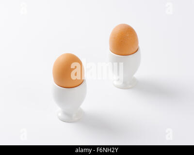 two boiled eggs in egg cups on white background Stock Photo