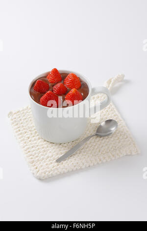 mug of strawberries in chocolate pudding on white table mat Stock Photo