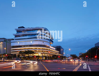 Exterior elevation across busy intersection at dusk. BreadTalk IHQ, Singapore, Singapore. Architect: Kay Ngeee Tan Architects, 2 Stock Photo