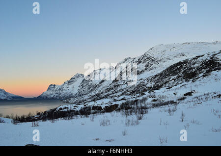 Beautiful landscape photo with high mountains and colorful dawn sky with blue fjord in the bottom Stock Photo