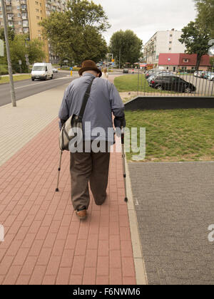 Elderly man walks with crutches down a street in Zielona Gora, Poland. Stock Photo