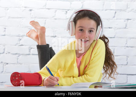 Young girl with headset doing homework on floor Stock Photo