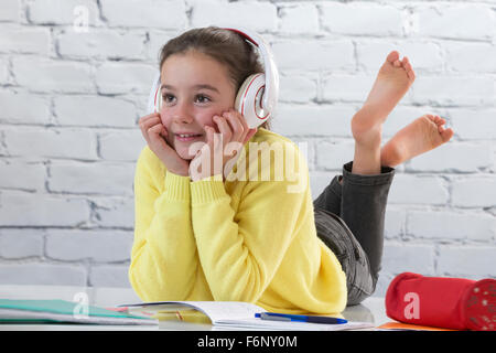 Young girl with headset doing homework on floor Stock Photo
