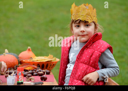 Girl creating crafts with chestnuts and pumpkin. Stock Photo