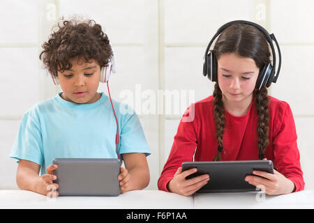 Siblings using digital tablet while listening music Stock Photo