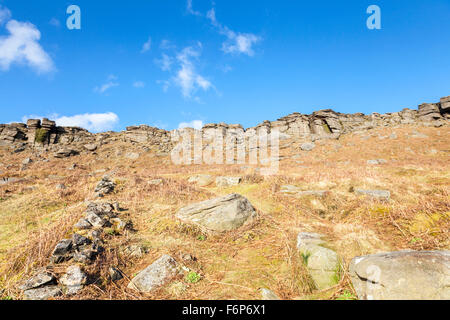 A hillside of old bracken on moorland with Stanage Edge, a gritstone escarpment, in the distance. Derbyshire, Peak District, England, UK Stock Photo