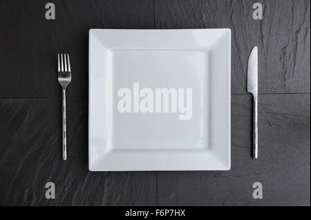 Overhead view of white square plate, knife and fork. Stock Photo