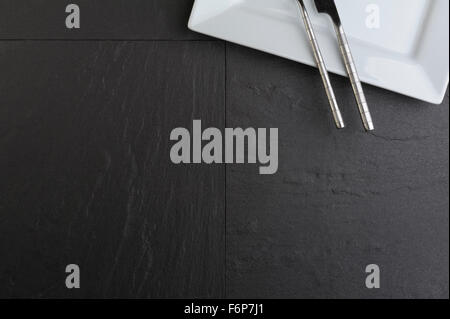 Overhead view of white square plate, knife and fork. Stock Photo