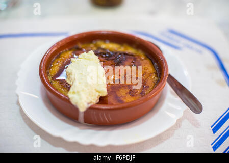 Crema Catalana or Creme Brulee in rustic bowl, typical taberna or bistro presentation with a chantilly spoonful. Traditional des Stock Photo