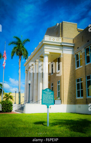 The Neo-Classical Charlotte County Courthouse building with historical marker, flag and blue skies in Punta Gorda, Florida Stock Photo