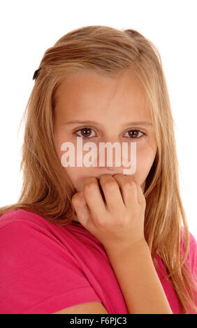 A scaret young girl in a pink sweater in a closeup picture biting her fingernails, isolated for white background. Stock Photo