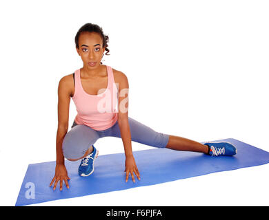 An African woman kneeling on a mat where rice is dried Stock Photo