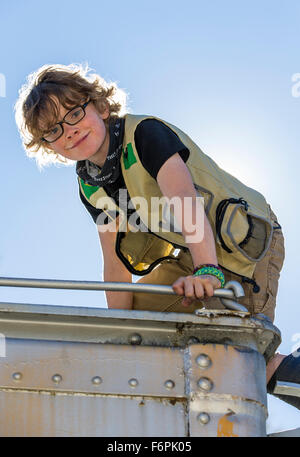 Backlit view of happy eight-year-old boy climbing on old rail train car Stock Photo