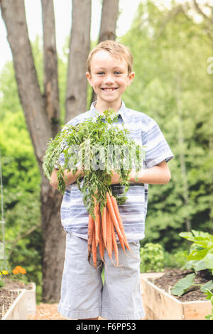 Caucasian boy holding carrots in garden