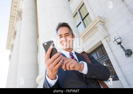 Mixed race businessman using cell phone outside courthouse Stock Photo