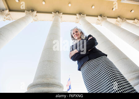 Low angle view of Caucasian businesswoman standing under columns Stock Photo