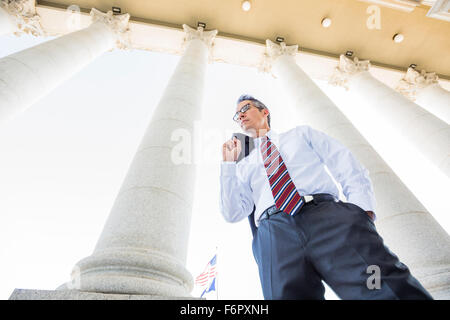 Low angle view of mixed race businessman standing under columns Stock Photo