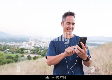 Mixed race man using cell phone on hilltop Stock Photo