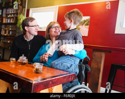 Paraplegic mother holding son in tea shop Stock Photo